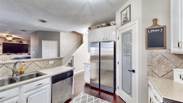 kitchen featuring a textured ceiling, white cabinets, appliances with stainless steel finishes, decorative backsplash, and sink