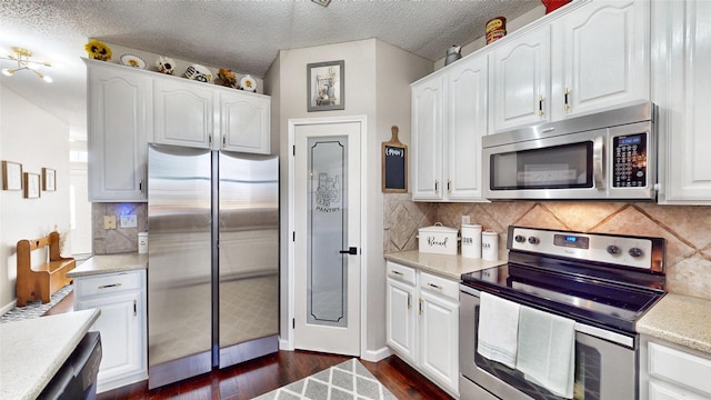 kitchen featuring a textured ceiling, appliances with stainless steel finishes, and white cabinets