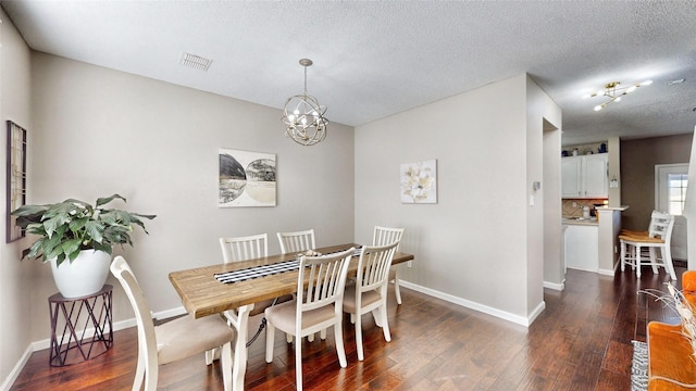 dining room featuring dark wood-type flooring, a textured ceiling, and a chandelier