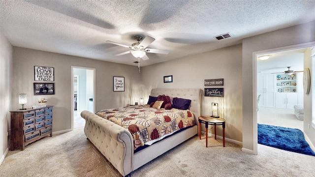 carpeted bedroom with ceiling fan, ensuite bath, and a textured ceiling