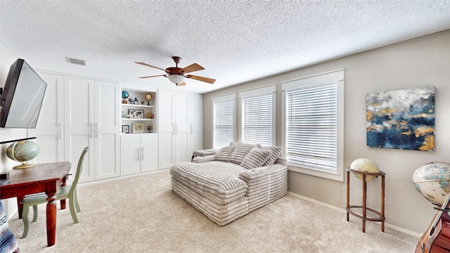 living area featuring a textured ceiling, ceiling fan, and light colored carpet