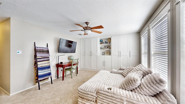 living area with ceiling fan, a textured ceiling, and light carpet