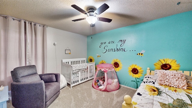 carpeted bedroom featuring ceiling fan, a crib, and a textured ceiling