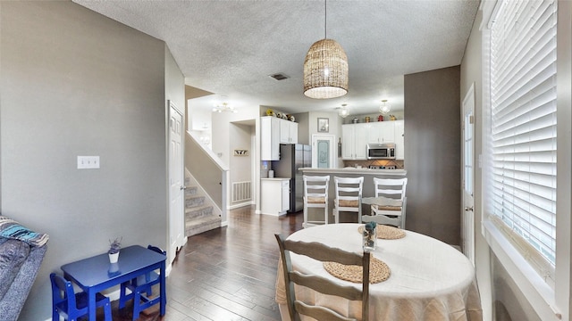 dining space featuring a textured ceiling and dark hardwood / wood-style flooring