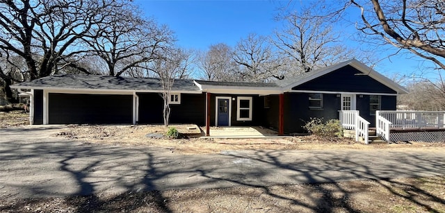 ranch-style home featuring a garage and a wooden deck