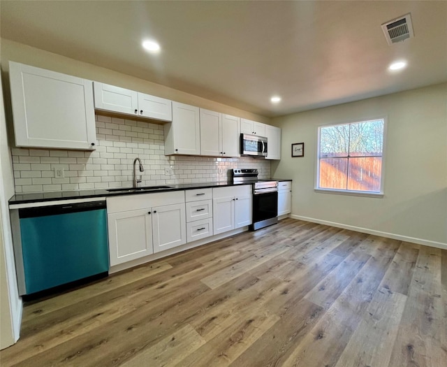 kitchen with white cabinets, sink, light wood-type flooring, tasteful backsplash, and stainless steel appliances