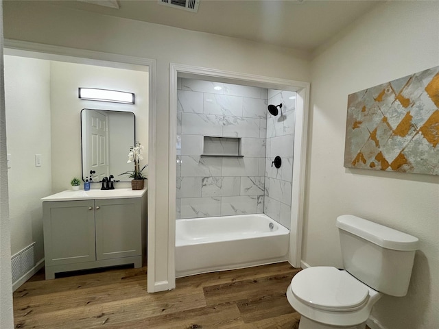 full bathroom with vanity, tiled shower / bath combo, hardwood / wood-style flooring, and toilet