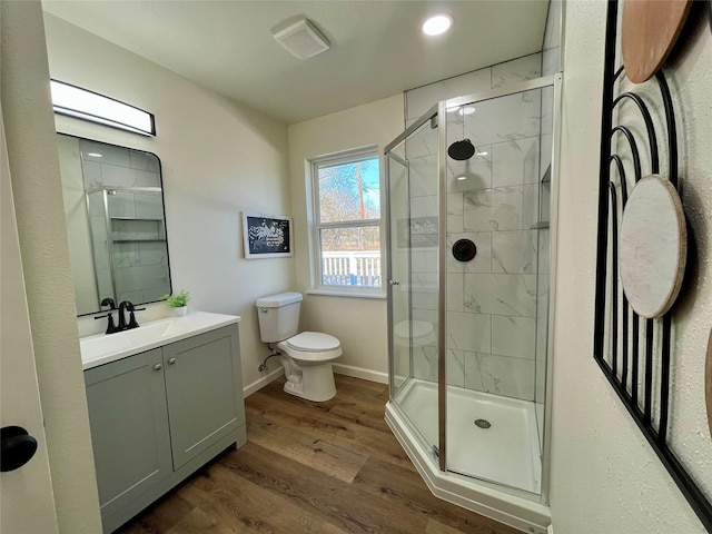 bathroom featuring hardwood / wood-style floors, vanity, toilet, and a shower with door