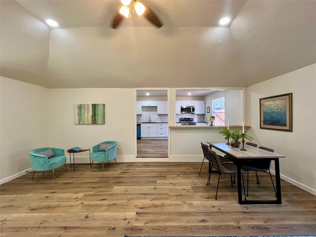 dining space featuring ceiling fan, light wood-type flooring, a textured ceiling, and vaulted ceiling