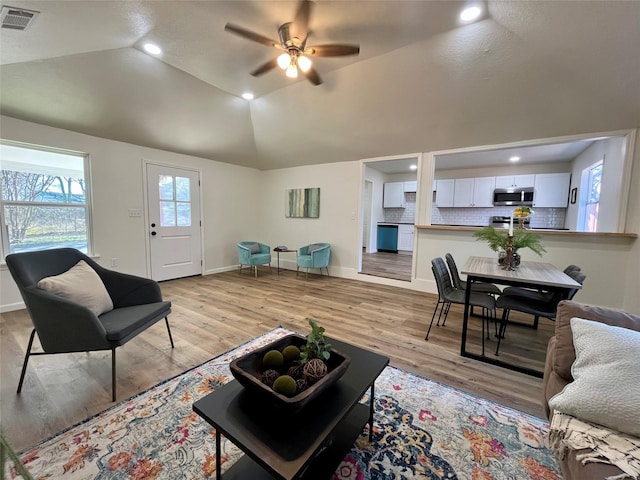 living room featuring ceiling fan, light hardwood / wood-style floors, and vaulted ceiling