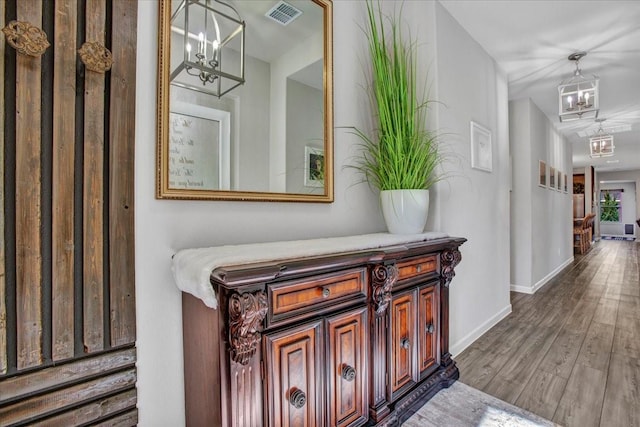 hallway with wood-type flooring and an inviting chandelier