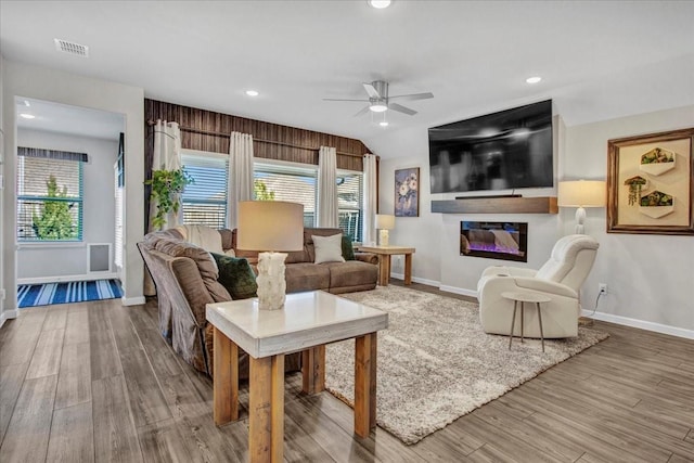 living room with hardwood / wood-style flooring, vaulted ceiling, ceiling fan, and a healthy amount of sunlight