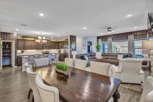 dining area featuring ceiling fan with notable chandelier and wood-type flooring