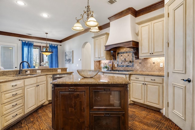 kitchen featuring light stone counters, sink, premium range hood, and pendant lighting