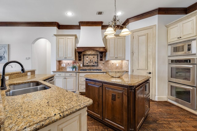 kitchen featuring pendant lighting, an inviting chandelier, premium range hood, sink, and a kitchen island with sink