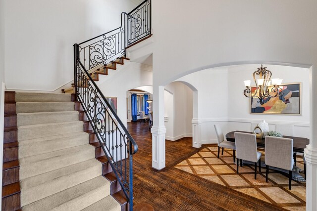 entryway with an inviting chandelier, a towering ceiling, and hardwood / wood-style flooring