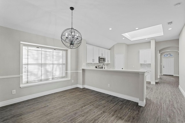 kitchen featuring kitchen peninsula, white cabinets, and dark wood-type flooring