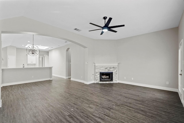 unfurnished living room with ceiling fan with notable chandelier, dark hardwood / wood-style floors, and a fireplace