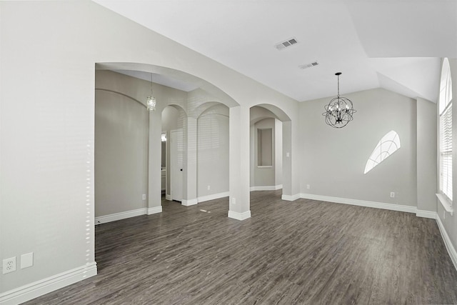 spare room with a chandelier, dark hardwood / wood-style floors, and vaulted ceiling