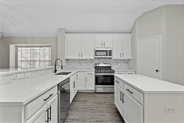 kitchen featuring appliances with stainless steel finishes, backsplash, sink, white cabinets, and lofted ceiling