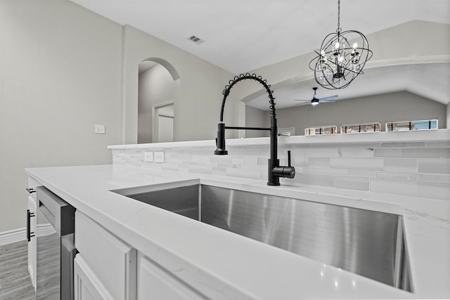 details featuring sink, stainless steel dishwasher, pendant lighting, white cabinets, and ceiling fan with notable chandelier