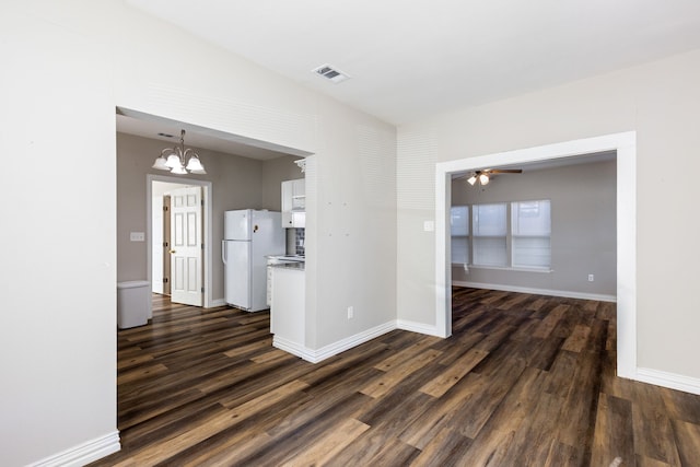 empty room with dark hardwood / wood-style floors and ceiling fan with notable chandelier