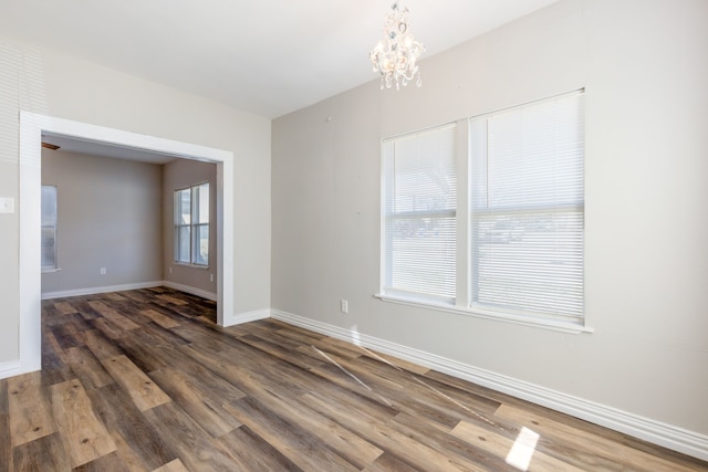 empty room with dark hardwood / wood-style floors and a chandelier