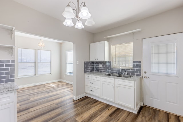 kitchen with sink, white cabinetry, hanging light fixtures, an inviting chandelier, and tasteful backsplash