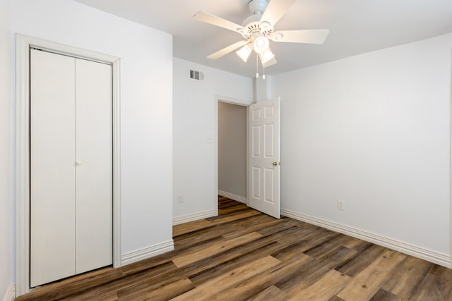 unfurnished bedroom with a closet, dark hardwood / wood-style floors, and ceiling fan