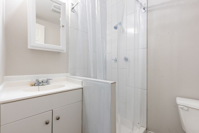 bathroom with walk in shower, vanity, and toilet