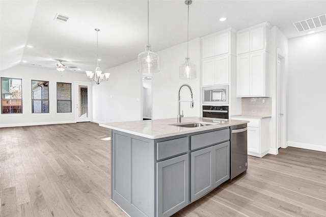 kitchen with sink, pendant lighting, a kitchen island with sink, white microwave, and ceiling fan with notable chandelier