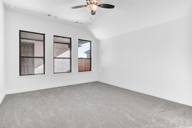 carpeted empty room with ceiling fan, a healthy amount of sunlight, and vaulted ceiling