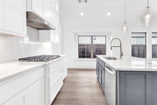 kitchen featuring appliances with stainless steel finishes, white cabinetry, sink, and range hood