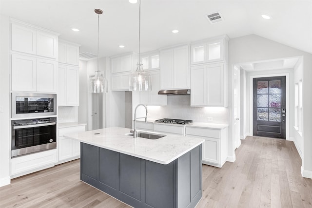 kitchen featuring white cabinetry, sink, light stone counters, a center island with sink, and appliances with stainless steel finishes