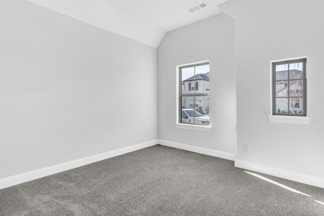 carpeted empty room featuring plenty of natural light and vaulted ceiling