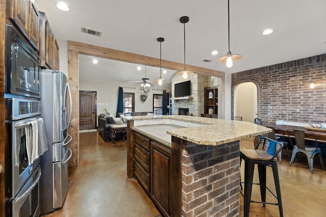 kitchen featuring pendant lighting, a center island, a breakfast bar area, light stone countertops, and stainless steel appliances