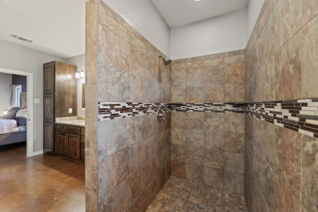 bathroom with a tile shower, vanity, and concrete flooring