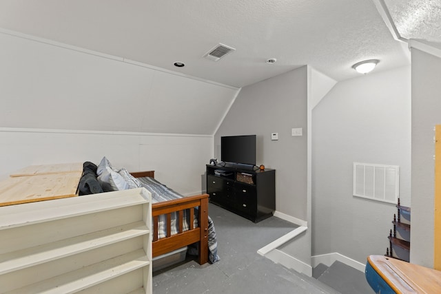 bedroom featuring a textured ceiling, concrete floors, and lofted ceiling