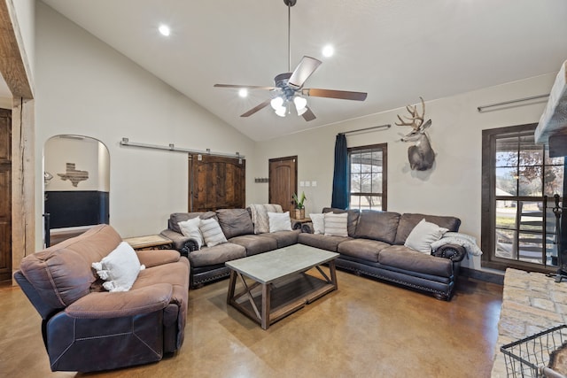 living room with a barn door, high vaulted ceiling, concrete floors, and ceiling fan