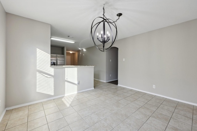 tiled empty room with a notable chandelier