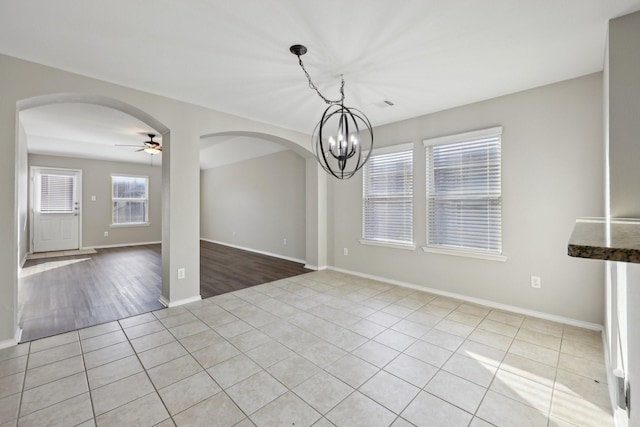 unfurnished dining area featuring ceiling fan with notable chandelier and light tile patterned floors