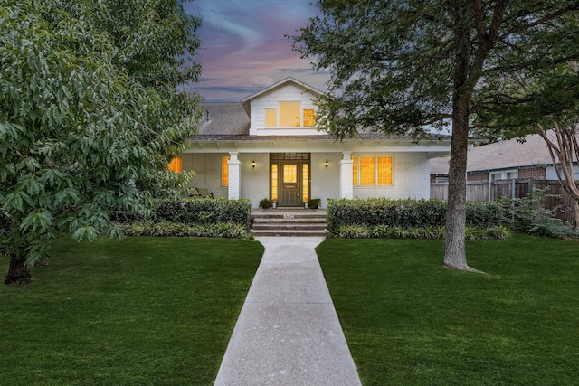 view of front of home featuring covered porch and a yard