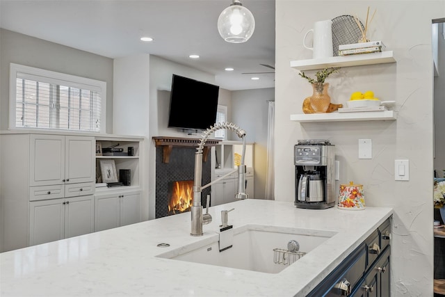 kitchen with light stone countertops, sink, and hanging light fixtures