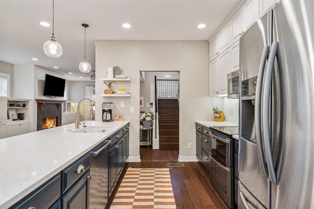 kitchen featuring sink, light stone counters, pendant lighting, white cabinets, and appliances with stainless steel finishes