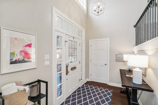 entryway featuring a towering ceiling, dark hardwood / wood-style flooring, and an inviting chandelier