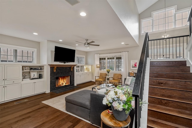 living room featuring dark hardwood / wood-style flooring, lofted ceiling, a fireplace, and ceiling fan with notable chandelier