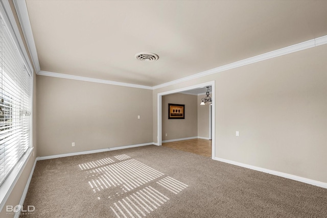 empty room featuring a chandelier, ornamental molding, carpet floors, and a healthy amount of sunlight