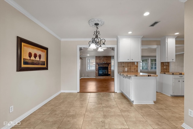 kitchen with white cabinetry, tasteful backsplash, kitchen peninsula, pendant lighting, and a chandelier