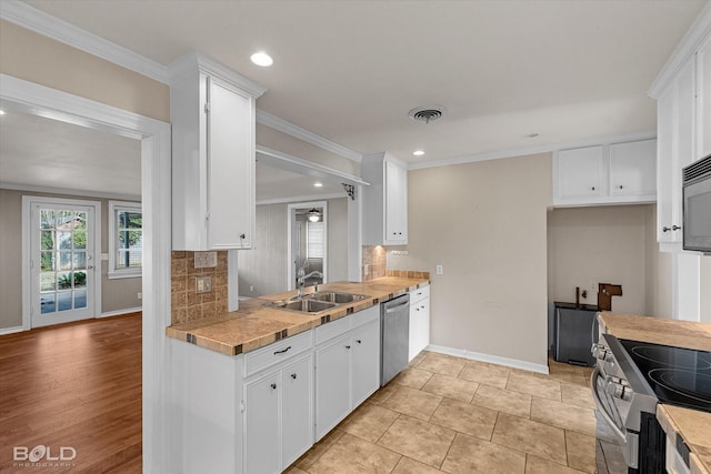 kitchen with decorative backsplash, sink, white cabinets, and stainless steel appliances