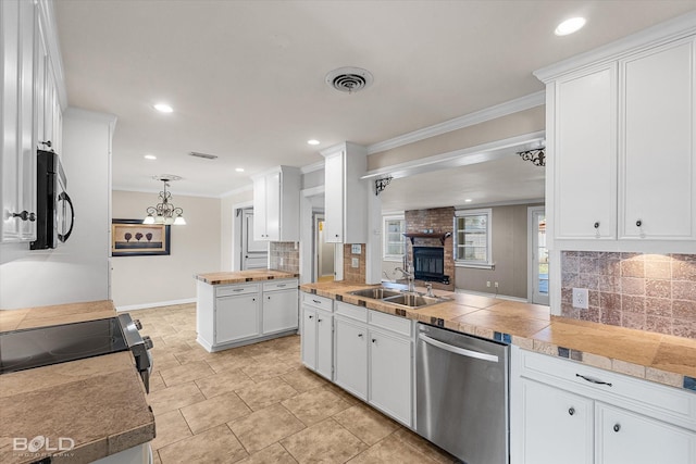 kitchen with appliances with stainless steel finishes, sink, white cabinets, hanging light fixtures, and ornamental molding